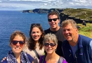 Peggy Bell with family smiling to camera on cliffside on vacation