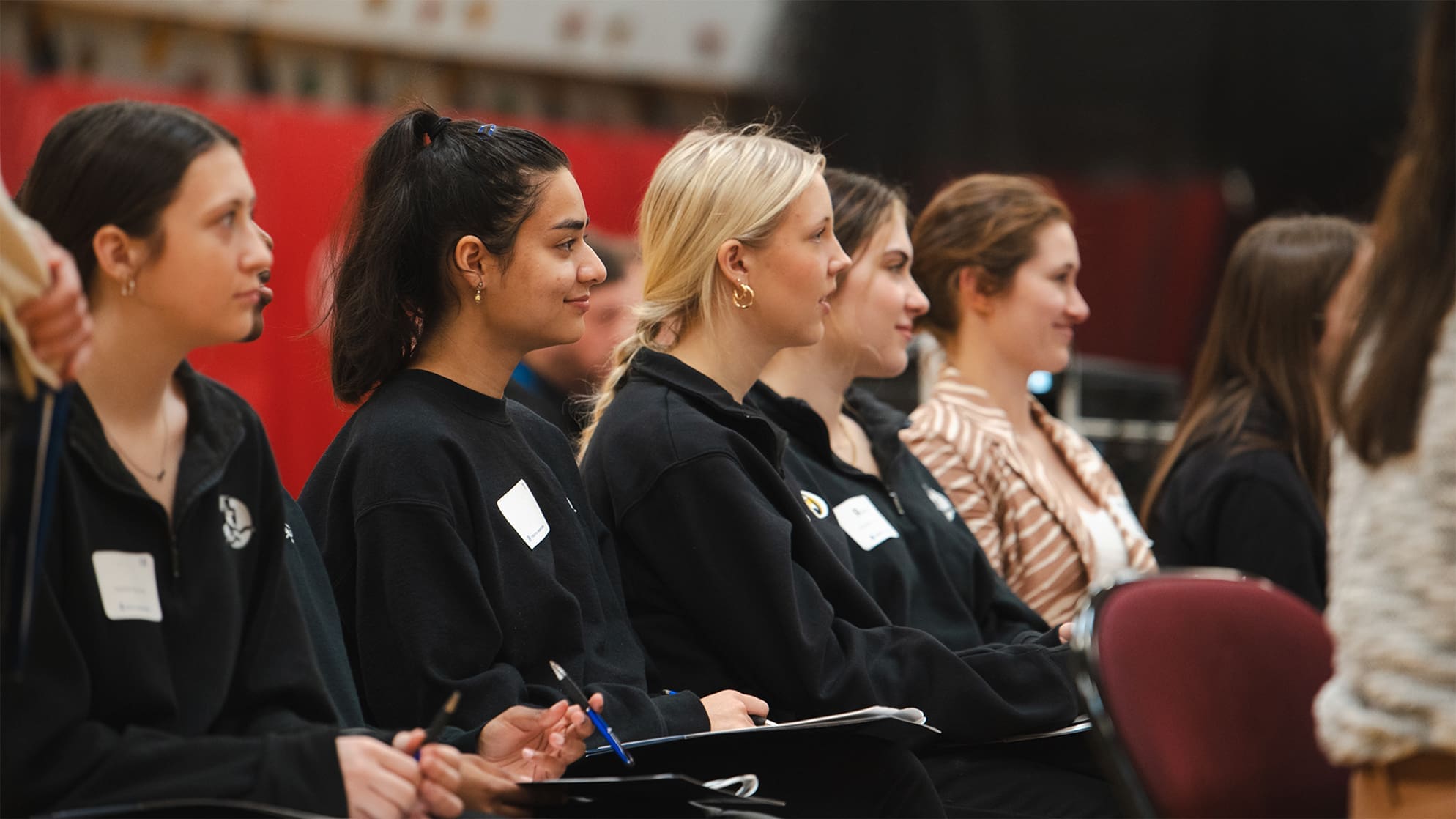 event photo yw cac a group of high school women are seated in a row facing to the right smiling while listening to a presentation